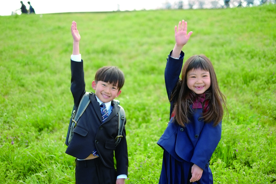 緑の芝生で笑顔を見せる二人の子ども(パンフレット掲載写真)